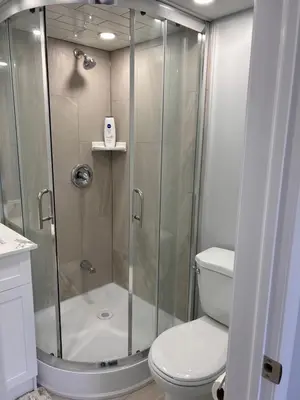 a shower with a glass door next to a toilet at Whitby Hideout - 3BR, 5BD, 3WR, Pool Table, Sauna in Whitby