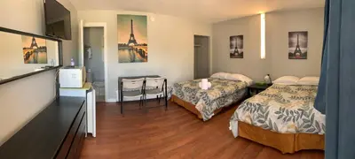 a room with two beds and a desk with a television at Wasaga Motel Inn in Wasaga Beach