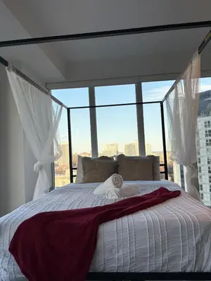 a bedroom with a white bed with a large window at Sweetheart studio with city views in Toronto