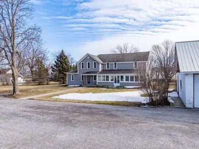 a large white house with a driveway in front of it at Vintage 8BR Farmhouse With Hot Tub Spacious Yard in Port Colborne
