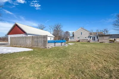 a house with a fence and a yard at Vintage 8BR Farmhouse With Hot Tub Spacious Yard in Port Colborne