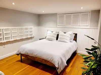 a bedroom with a bed with white sheets and pillows at Charming Basement Studio Bathroom Full Kitchen in Toronto