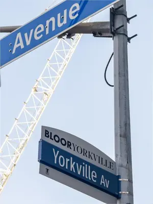 two blue street signs on a pole with a crane at Discounted Elegant Yorkville Suite in Toronto