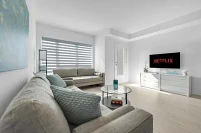 a living room with a couch and a tv at Stylish 4-Bed Home with Backyard in Prime Location in Burlington