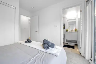 a white bedroom with a large bed with blue pillows at Stylish 4-Bed Home with Backyard in Prime Location in Burlington