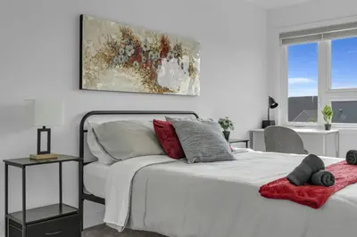 a white bedroom with a bed and a painting on the wall at Stylish 4-Bed Home with Backyard in Prime Location in Burlington