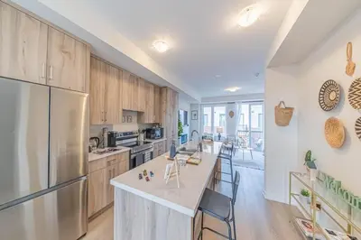 a kitchen with wooden cabinets and a large island with bar stools at Entire home in Oakville, Canada in Oakville