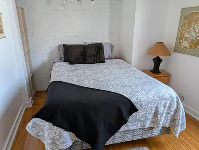 a bedroom with a bed with a black blanket on it at Cozy 2-Bedroom Downtown Apartment in London