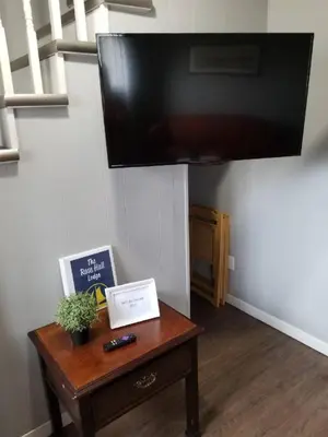 a living room with a table and a flat screen tv at The Rosehall PEC Waterfront Stay in Wellington