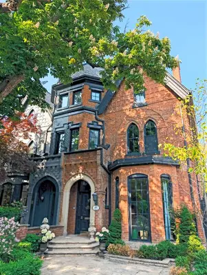 a red brick house with a tree in front of it at Hazelton Heritage in Toronto