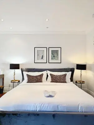 a bedroom with a large white bed with two lamps at Hazelton Heritage in Toronto