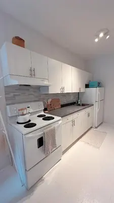 a kitchen with a white stove and white cabinets at Cozy Coach House in Kitchener