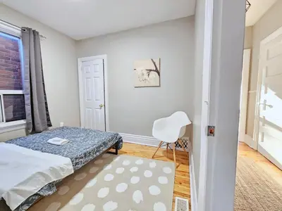 a bedroom with a bed and a white chair at Downtown Toronto Apartments in Toronto