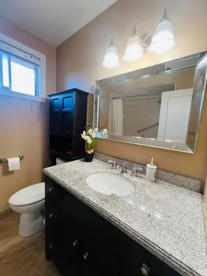 a bathroom with a sink and a toilet and a mirror at Cozy Stay, Self Check-In with Parking available upon request in Toronto