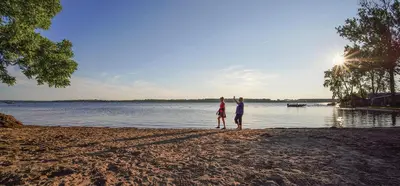 two people standing on a beach near the water at Scugog Landing Resort in Port Perry