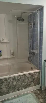 a bath tub with a shower in a bathroom at 2 bdrm apartment 3 min walk to McMaster University in Hamilton
