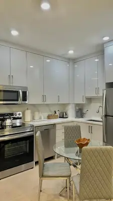 a kitchen with white cabinets and a glass table and chairs at Bright Luxurious 2 Bedroom Apartment in Toronto