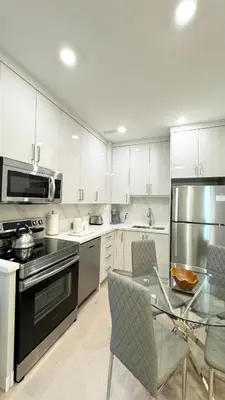 a kitchen with white cabinets and a glass table with chairs at Bright Luxurious 2 Bedroom Apartment in Toronto