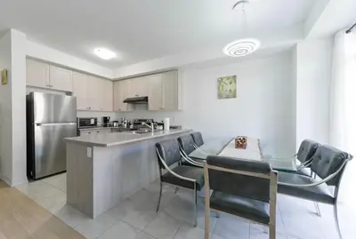 a kitchen with a table and chairs and a refrigerator at Modern Home 10 mins from Niagara Falls & Main Attraction with Free 2 Parkings in Thorold