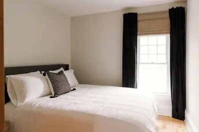 a bedroom with a bed with white sheets and a window at SquirrelHaus PEC in Hillier