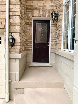 a black door on a brick house with stairs at Private Bright Coach House - Near Pearson Airport & Downtown Toronto in Brampton