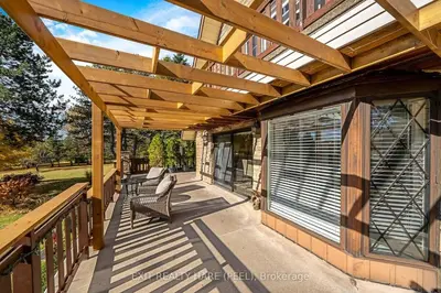 a wooden pergola on a porch with two chairs at Mono Farmhouse in Caledon