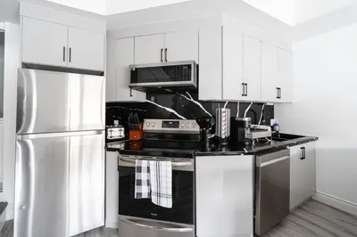 a kitchen with white cabinets and a stainless steel refrigerator at Luxury 2 Bedroom 3 Bed Family Friendly Oasis with Smart Technology in Brampton