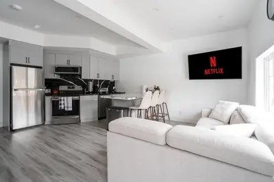 a living room with a white couch and a kitchen at Luxury 2 Bedroom 3 Bed Family Friendly Oasis with Smart Technology in Brampton