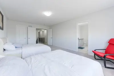 a bedroom with two beds and a red chair at Entire 4BR Detached Home 15 Mins from the Falls, in Thorold, Perfect for 10 guests in Thorold