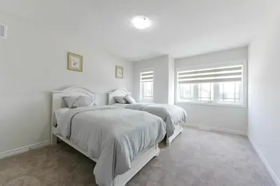 two beds in a white room with two windows at Entire 4BR Detached Home 15 Mins from the Falls, in Thorold, Perfect for 10 guests in Thorold