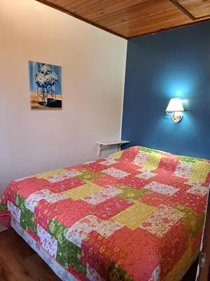 a bedroom with a bed with a colorful quilt at Wymbolwood Lodge in Tiny