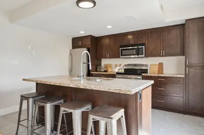 a kitchen with wooden cabinets and a counter with stools at Wintergreen Spacious 2 Story Townhome Sauna 2 Min Walk to Village in Blue Mountains