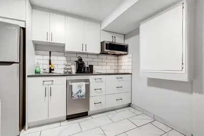 a white kitchen with white cabinets and a microwave at Luxury & private 3 bed basement unit kitchen, wifi, park, mall in London