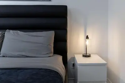 a bedroom with a bed with a lamp on a night stand at Modern 1BR and 1BA condo near Downtown with City Views in Toronto