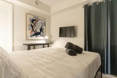 a bedroom with a white bed and a window at Chic 1BR plus Den Condo Near ROM and CN Tower in Toronto
