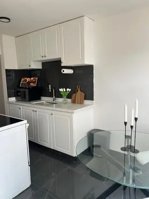 a kitchen with a glass table and white cabinets at Cozy Bohemian Apartment in Toronto