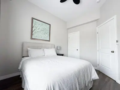 a white bedroom with a bed and a ceiling fan at Contemporary West Loft in Historic Niagara in Niagara on the Lake