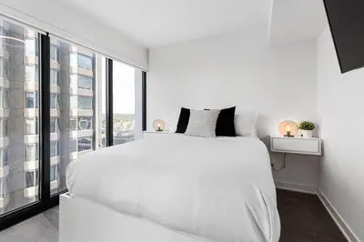 a white bedroom with a large bed and a large window at Executive 1BR-1BA Condo in the heart of downtown in Toronto