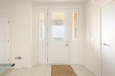 a white hallway with a white door and a rug at The Residence, Your comfort is our culture in Oakville