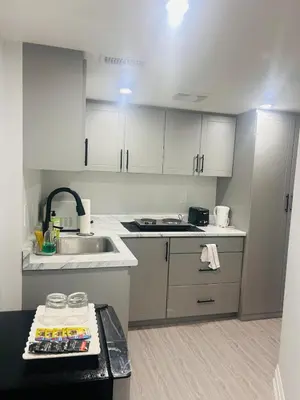 a small kitchen with white cabinets and a sink at The Sleek Shelter in Milton