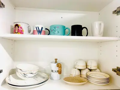 a kitchen shelf with dishes and cups and plates at The Sleek Shelter in Milton