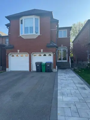 a house with two white garage gates in the driveway at Pearson Gateway Comfort Home in Mississauga
