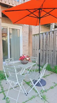 a table and chairs with an umbrella and a basket of flowers at Beautiful Studio with Patio in Mississauga in Mississauga