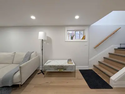 a white living room with a couch and stairs at The Urban Hideaway - Stylish Stay - Prime Spot in Hamilton