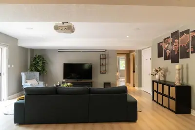 a living room with a black couch and a flat screen tv at Cozy Private Suite with Year-Round Hot Tub in Elora