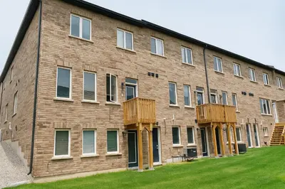 a large brick building with wooden balconies on it at 2024 Built Stylish 3BR Cambridge Townhouse with Free Parking, WiFi, Full Kitchen, Laundry, 8 Min Drive to African Lion Safari! Perfect for Family Travel, Group Trips & Work Stays! in Cambridge