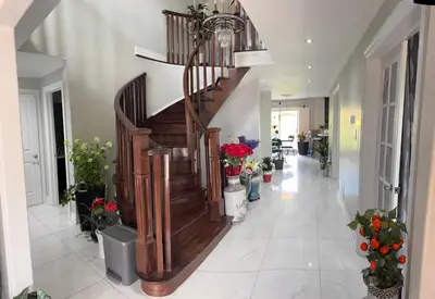 a hallway with a wooden staircase in a house with flowers at Master bedroom suite on the 2nd floor, city center in Mississauga