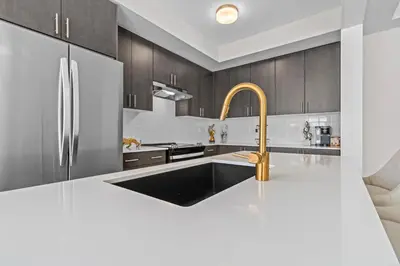 a kitchen with black and white cabinets and a gold faucet at Luxury Townhome in Oakville
