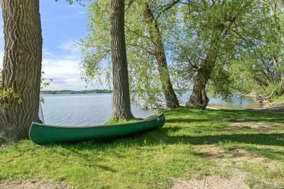 a green canoe sitting on the grass next to trees at The Sumac - 8 Natures in Cherry Valley