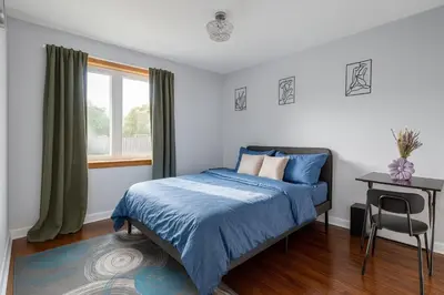 a bedroom with a bed and a table and a window at Newly Renovated 3BR North York Bungalow with Backyard Patio & Volleyball Set! Close to Rogers Stadium, TTC Subway Access, Perfect for Family Travel, Group Trips & Work Stays! in Toronto
